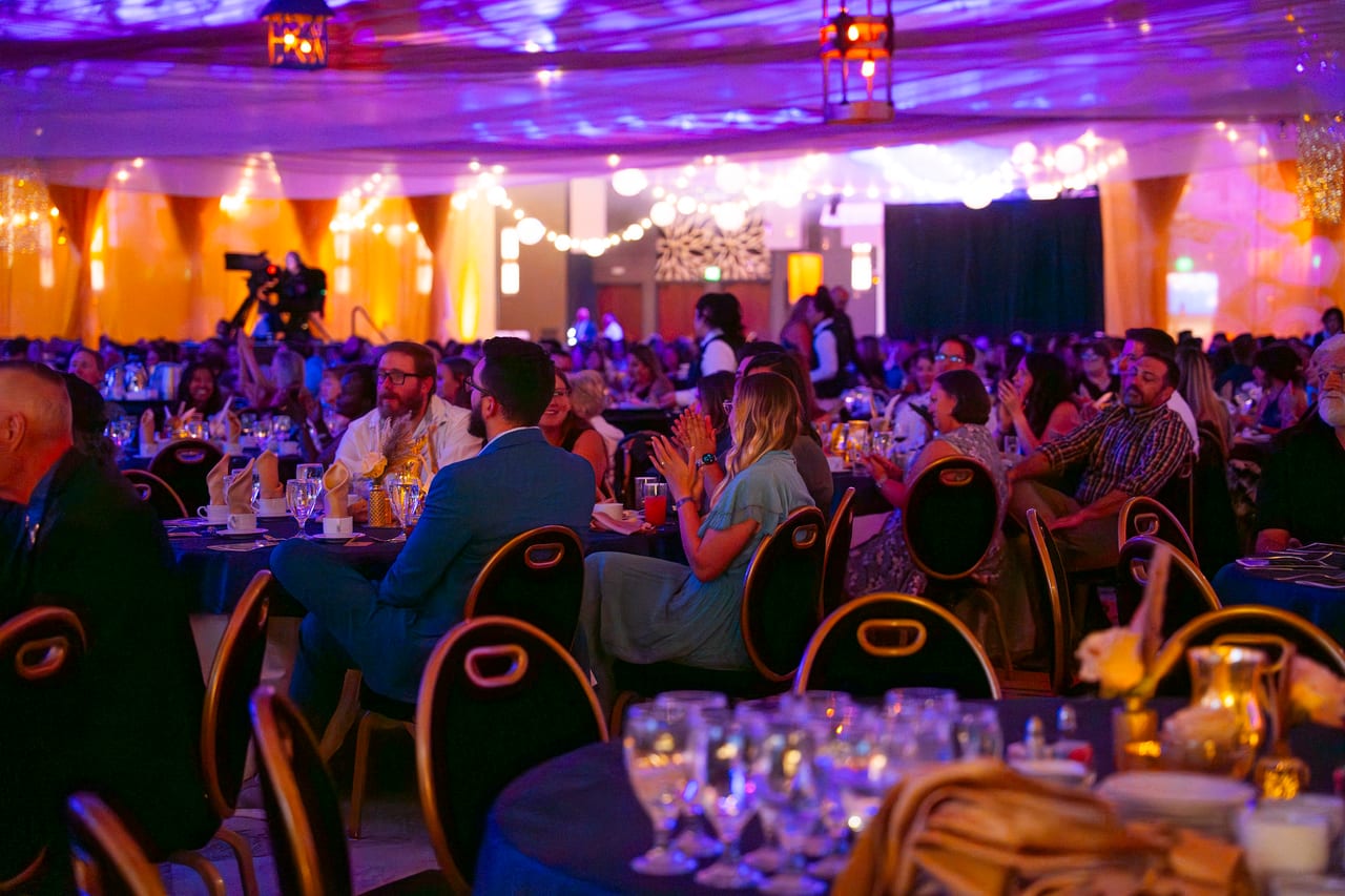 A full Tuscany Ballroom of Renown guests applauding at their tables