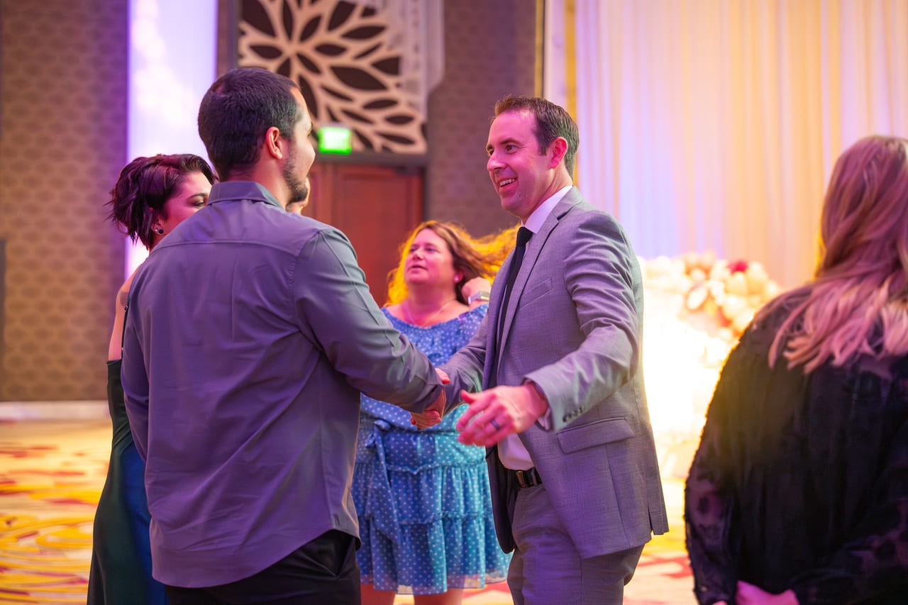 Renown coworkers greeting each other with handshakes in the ballroom