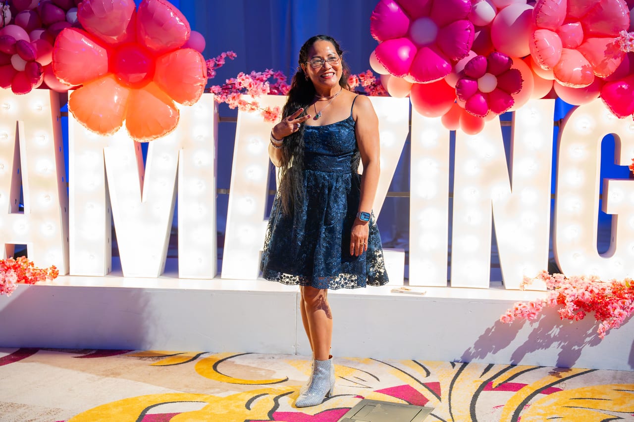 A Renown guest in a lace dress posing in front of the AMAZING letters