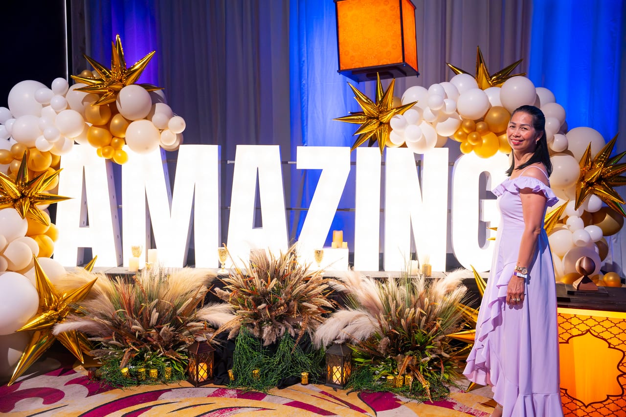 A Renown guest in a lavender gown posing at the AMAZING balloon arch