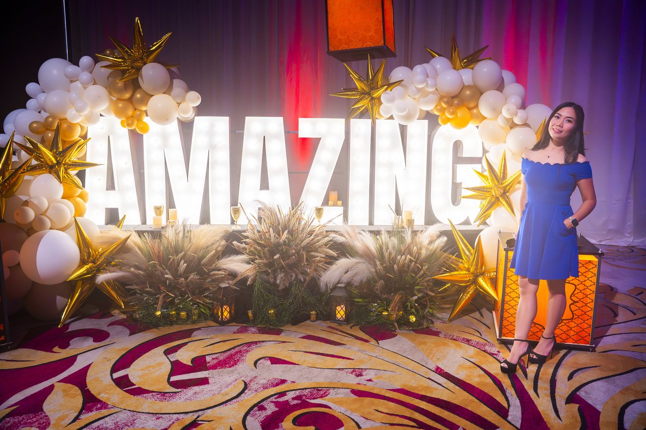 A Renown guest in a blue dress posing beside the Amazing letters