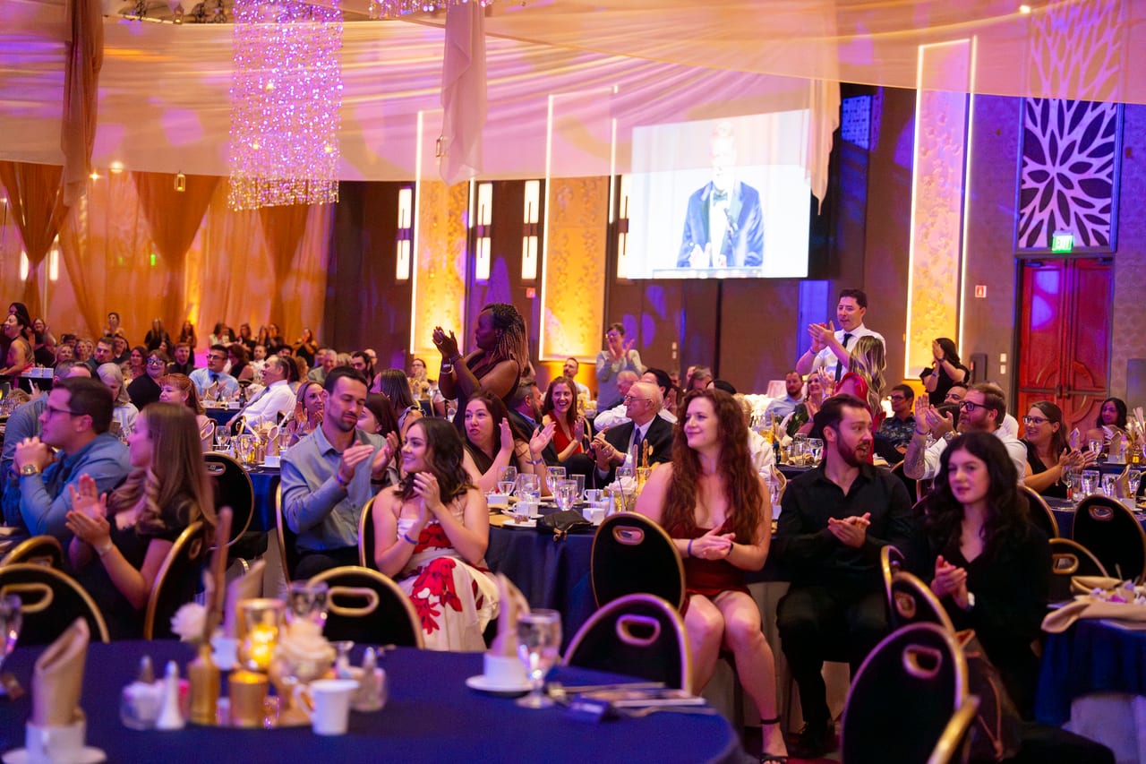 Renown guests applauding a speaker on the big screen