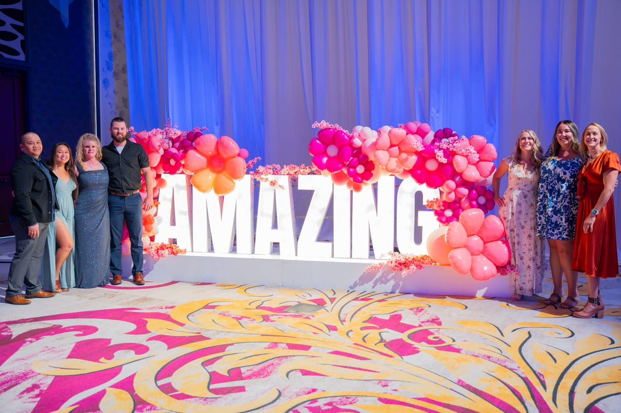 Renown guests posing at the lit AMAZING letters and the pink balloon wall