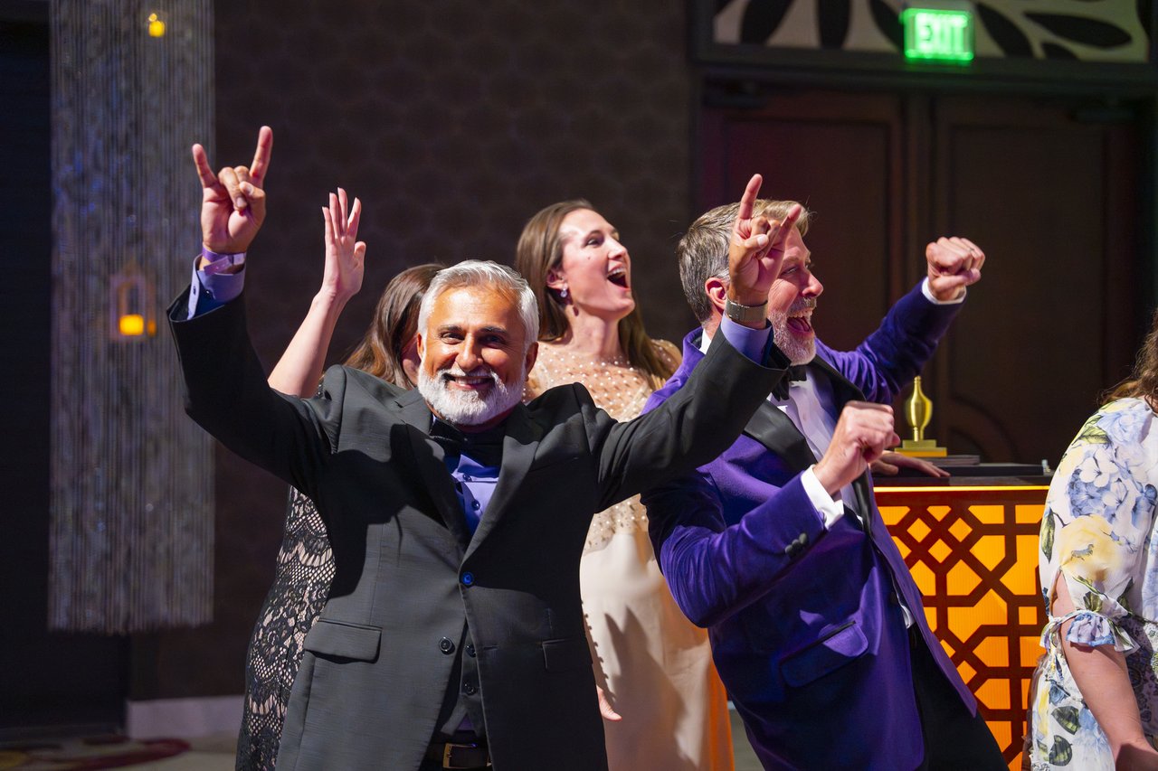 Renown guests cheering and throwing their hands up by the stage
