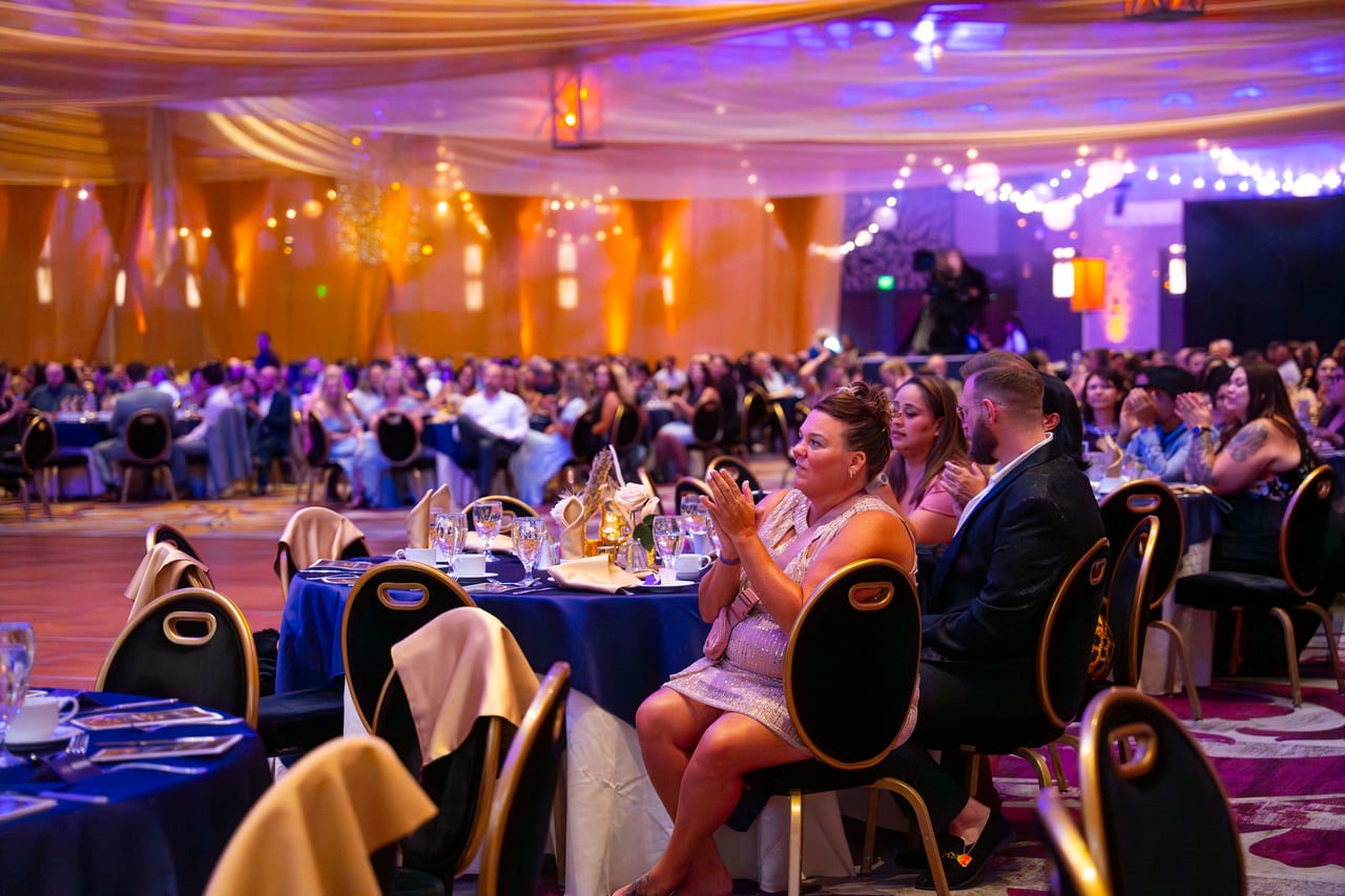 Renown guests clapping along at their tables in the golden ballroom