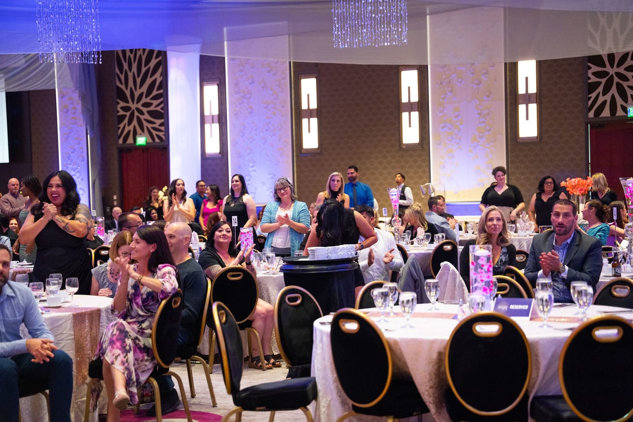 Renown guests standing and cheering at their tables in the ballroom