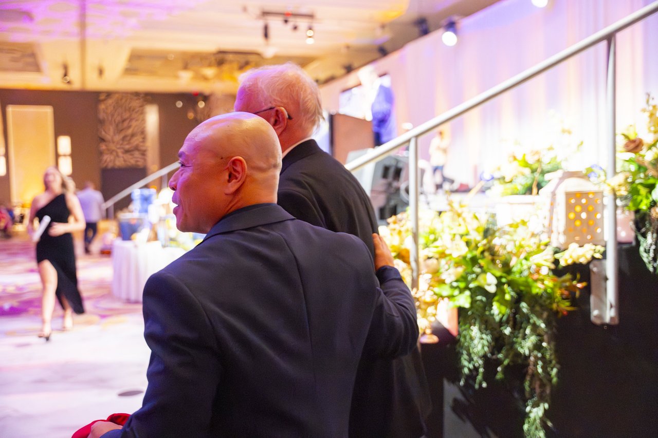 Two Renown guests watching the room from beside the stage rail