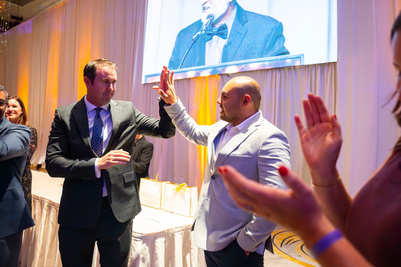 Two Renown coworkers trading a high five by the stage as the room claps