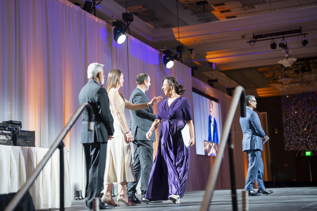 A Renown honoree greeted by leaders at the top of the stage stairs