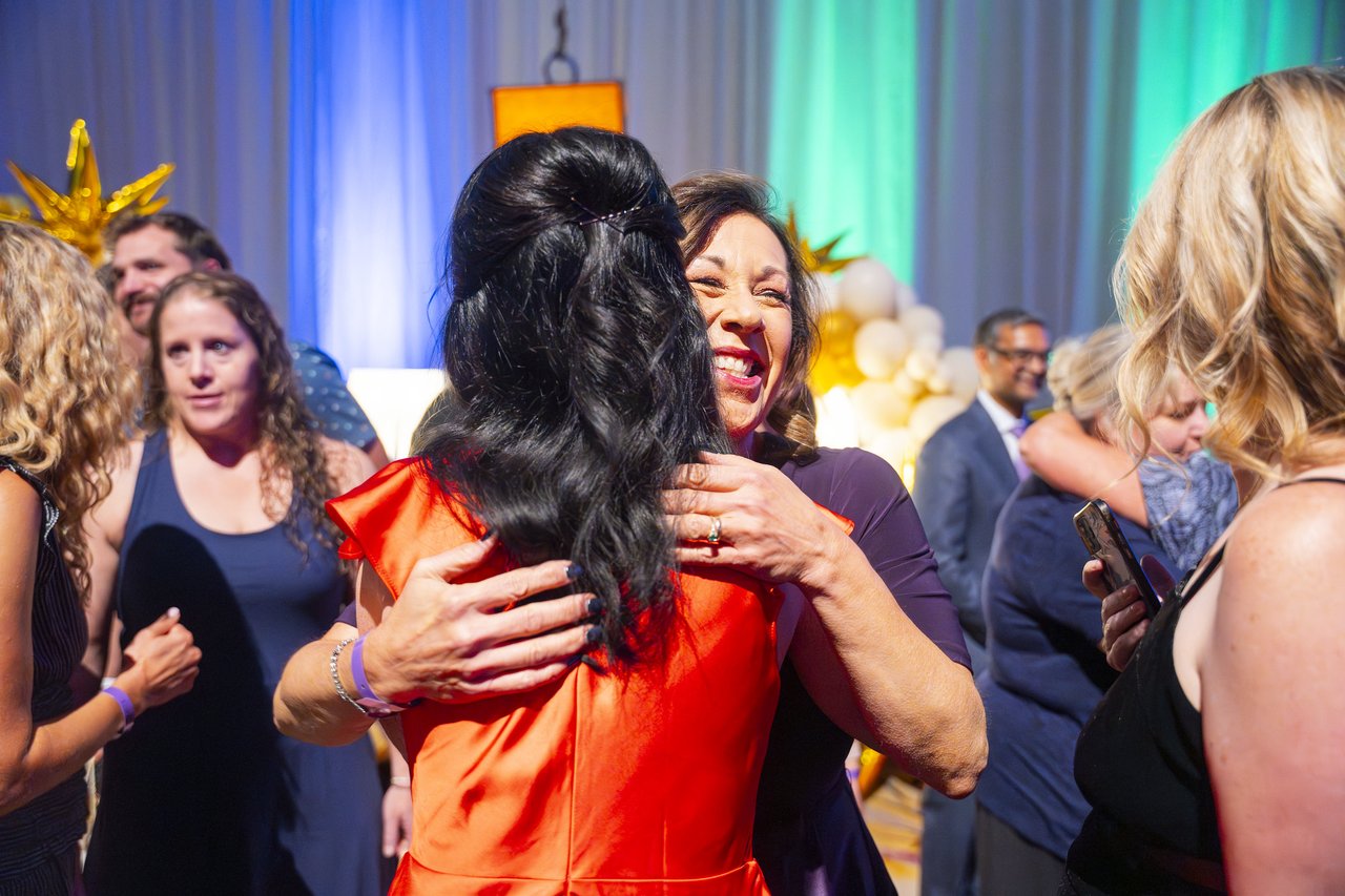 A Renown honoree in an orange dress hugging a coworker