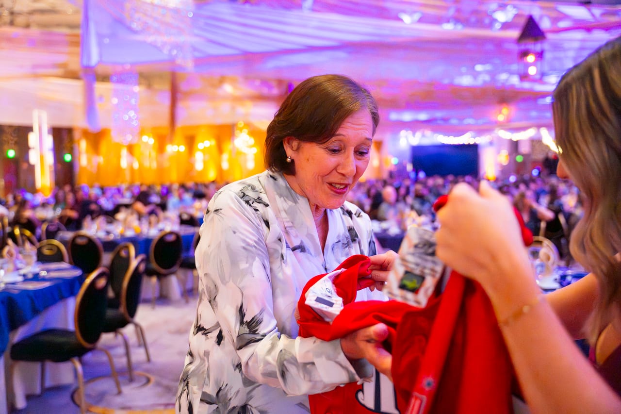 A Renown honoree smiling as she unwraps her gift at her table