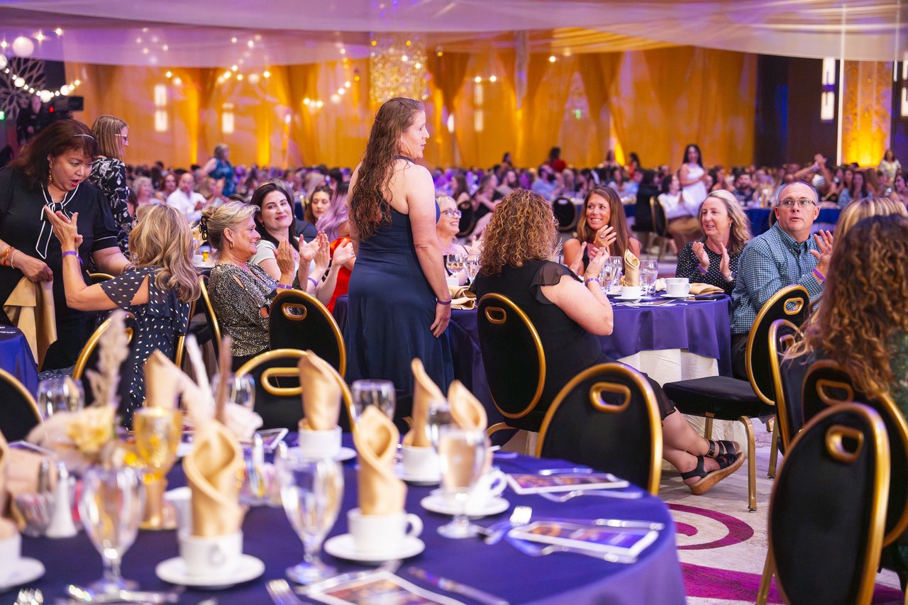 A Renown honoree standing at her table as the crowd applauds