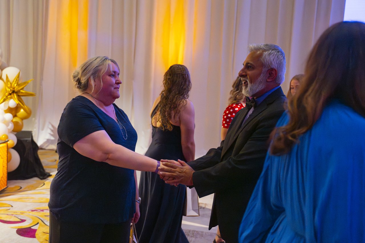A Renown honoree shaking hands with a leader beside the stage