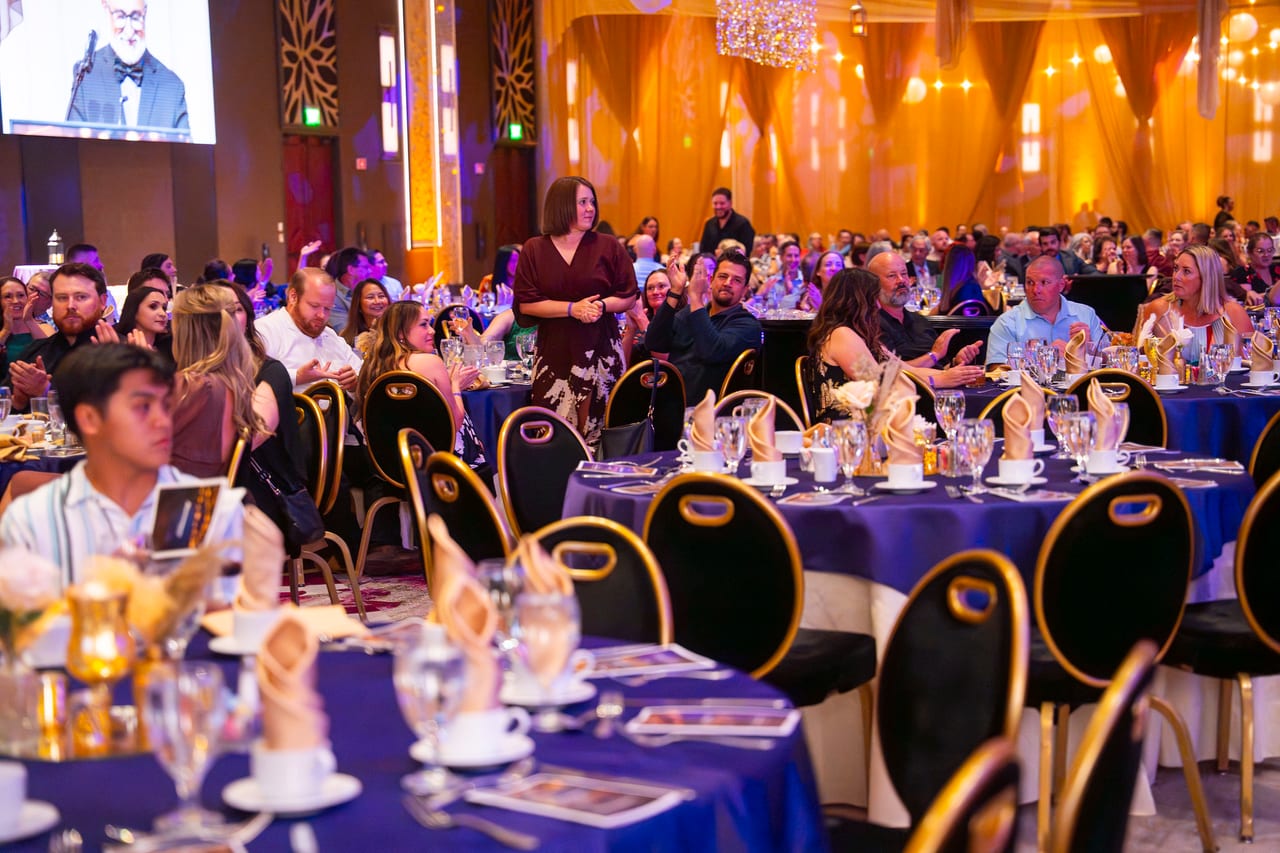 A Renown honoree standing at her table as the room celebrates her