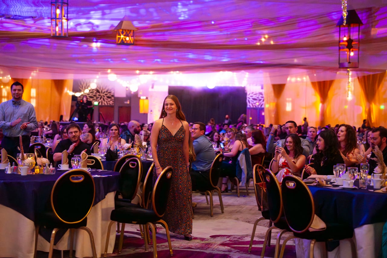 A Renown honoree walking to the stage through the cheering tables