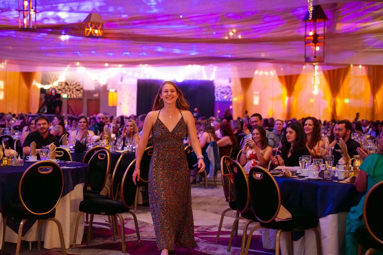 A Renown honoree smiling as she walks up through the tables