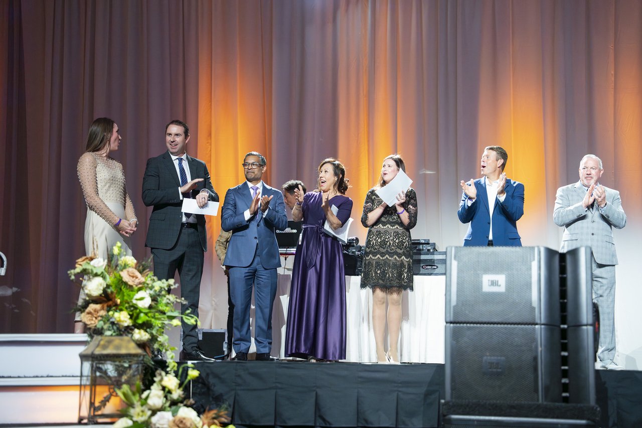Renown honorees applauding on stage behind the flowers