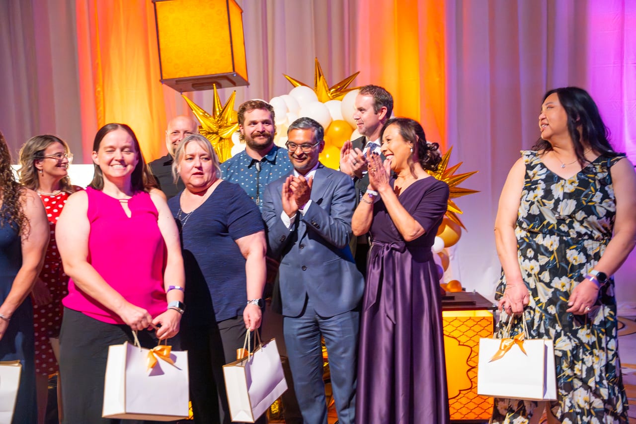 Renown honorees and leaders cheering together on stage with gift bags