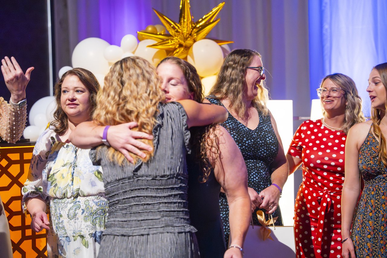 Renown honorees hugging and smiling at the gold balloon arch