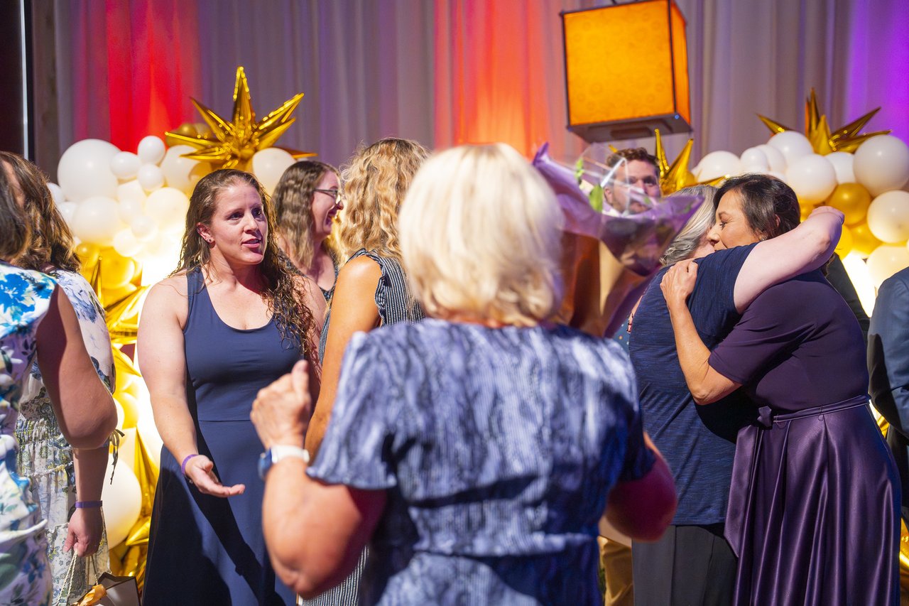 Renown honorees hugging beside the balloon wall
