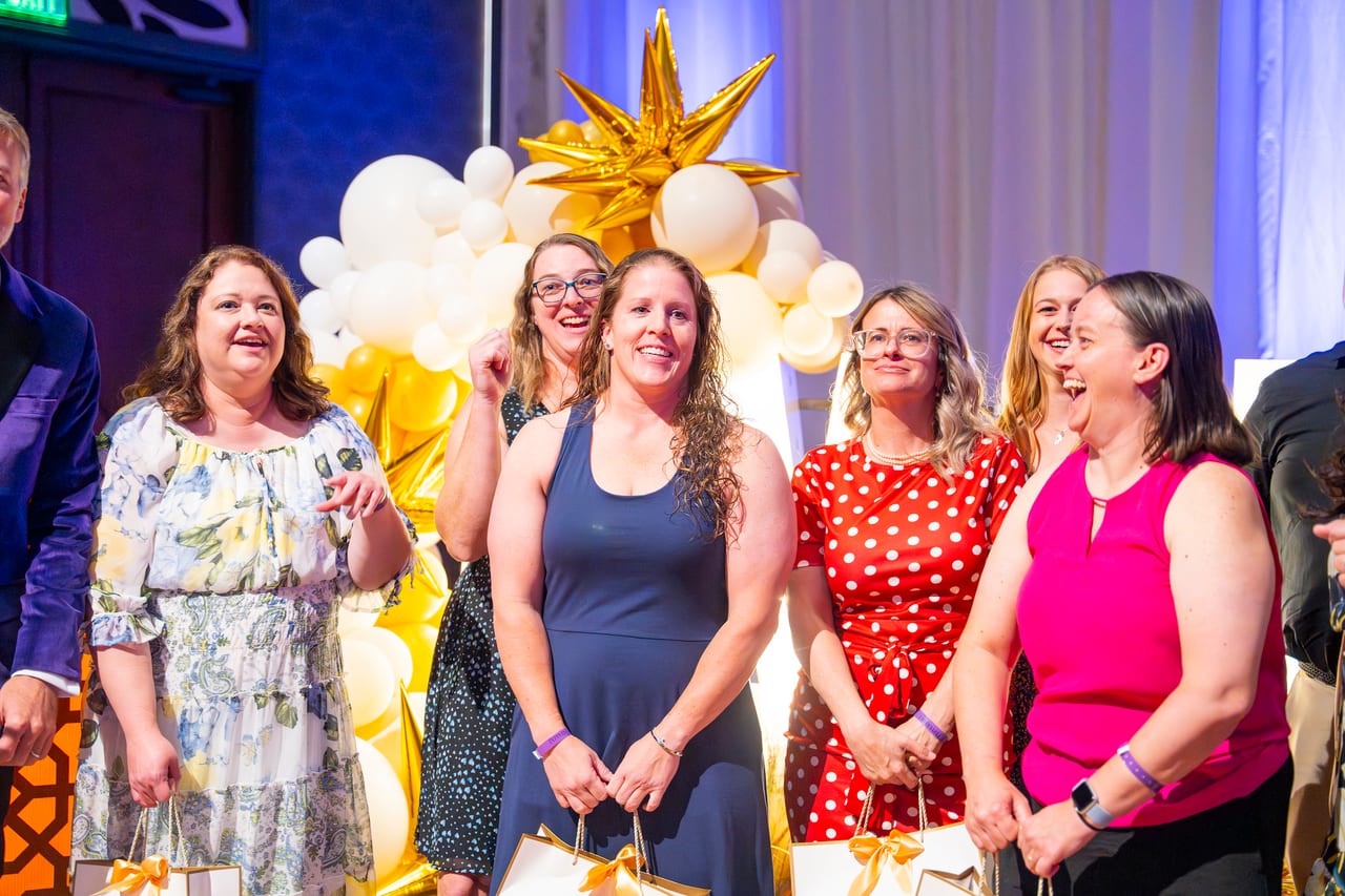 Renown honorees laughing together with their gift bags by the balloon wall