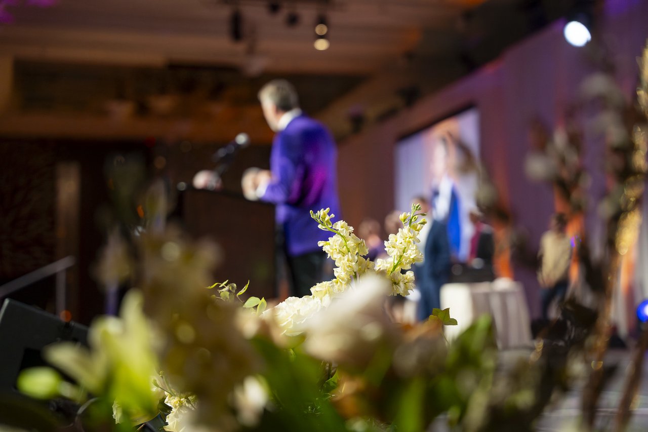 The host at the podium seen through the flowers