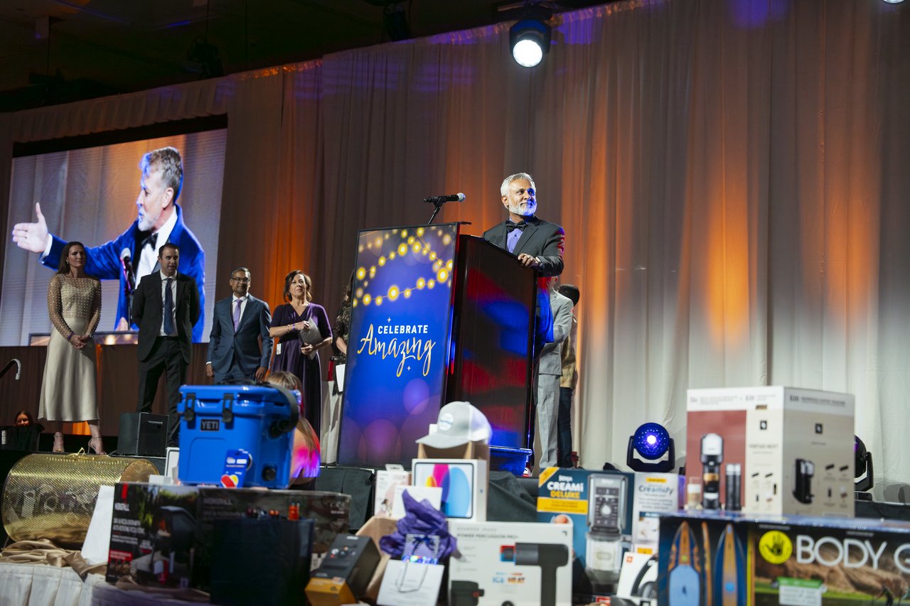 The host pointing on the big screen above the prize table