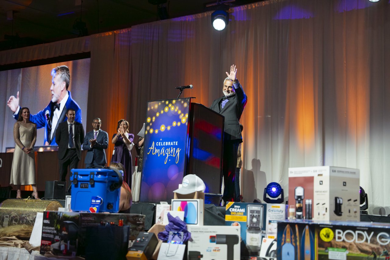 The host waving from the podium above the raffle prizes