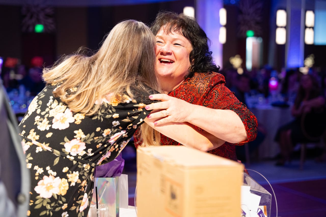 Two Renown coworkers sharing a big hug at the prize table