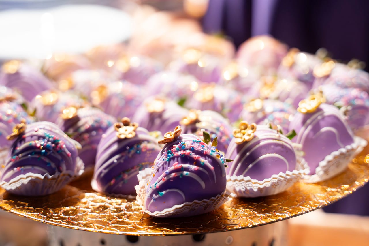 Lavender chocolate covered strawberries topped with tiny gold flowers