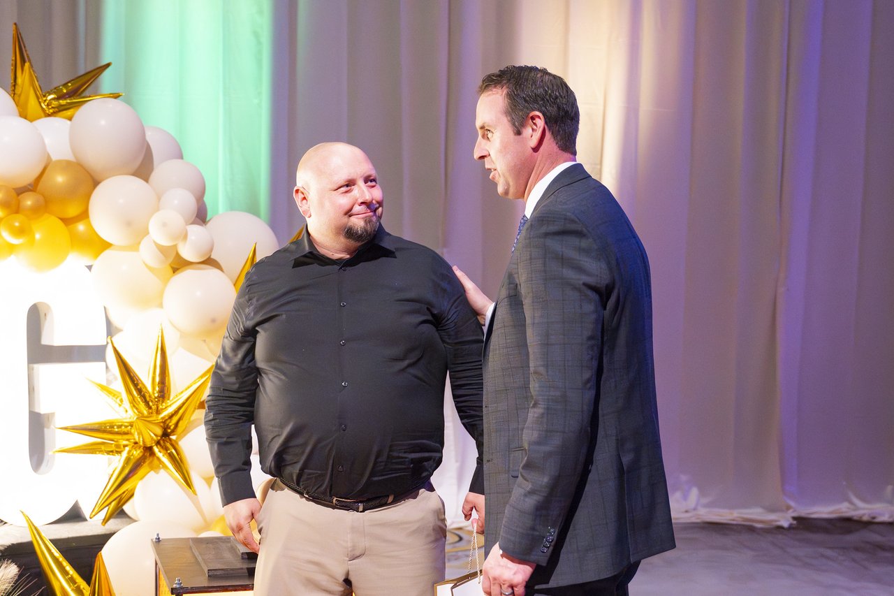 A Renown leader congratulating an honoree by the balloon arch