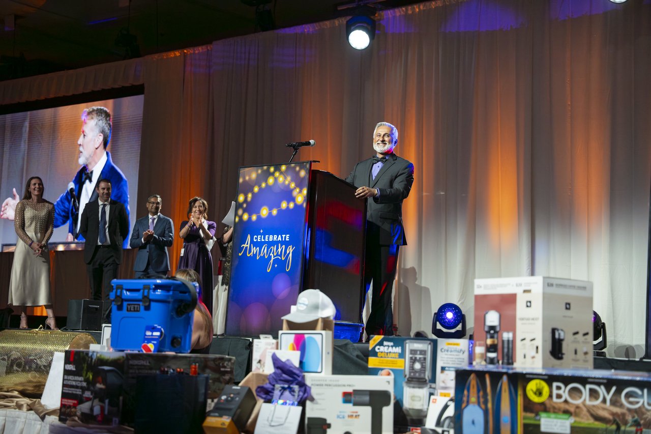 A Renown leader laughing at the podium above the prizes