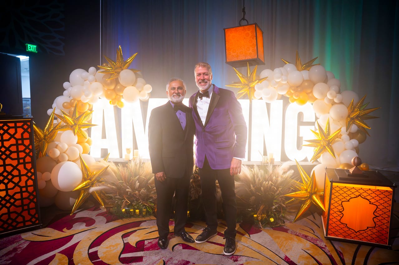 Two Renown leaders posing under the glowing AMAZING balloon arch