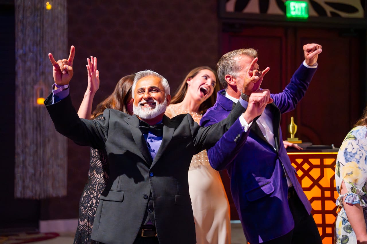 Renown leaders cheering with their hands in the air beside the stage
