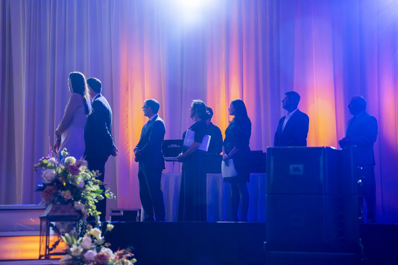 Renown leaders in silhouette against the lit stage curtains