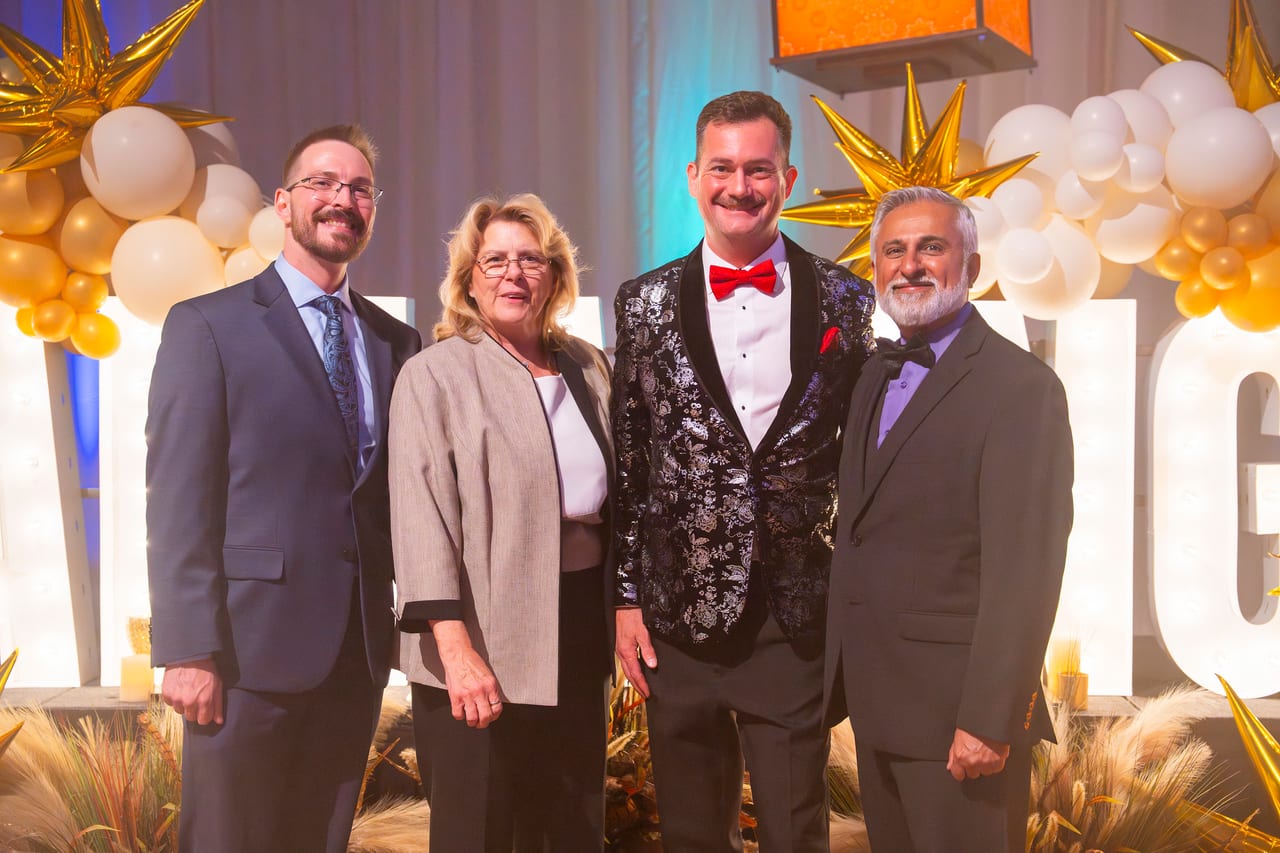 Four Renown leaders dressed up in front of the AMAZING letters