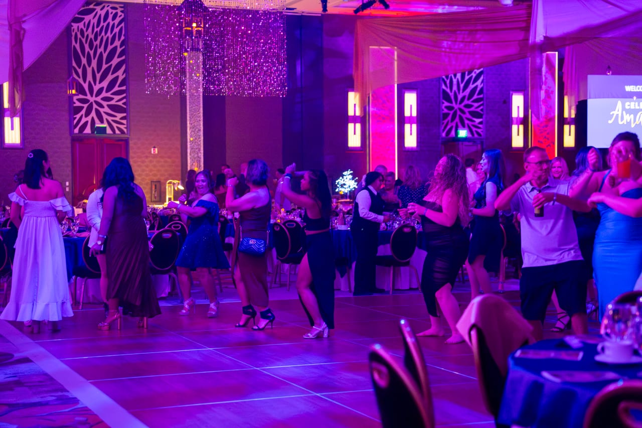 Renown guests dancing together across the floor under purple light