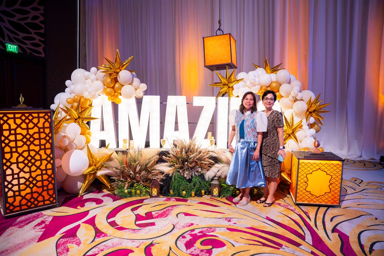 Two Renown guests posing at the AMAZING balloon arch between gold lanterns