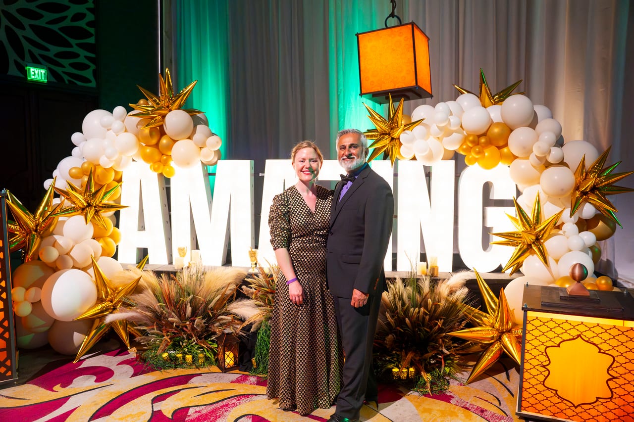 Two Renown guests posing at the AMAZING letters framed in gold star balloons