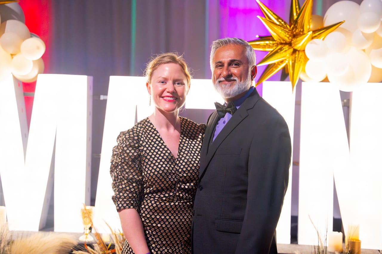 Two Renown guests posing close at the glowing white letters
