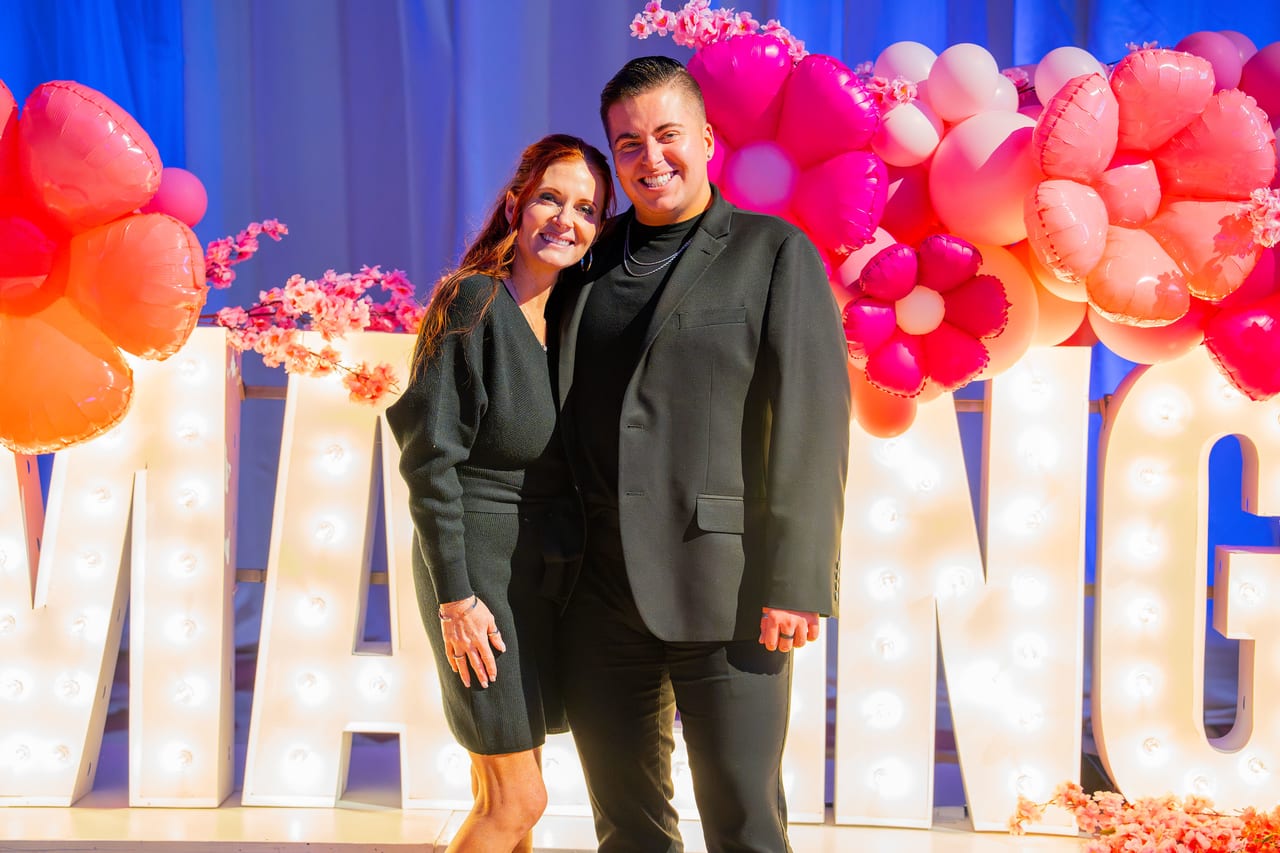 Two Renown guests smiling together in front of the lit letters
