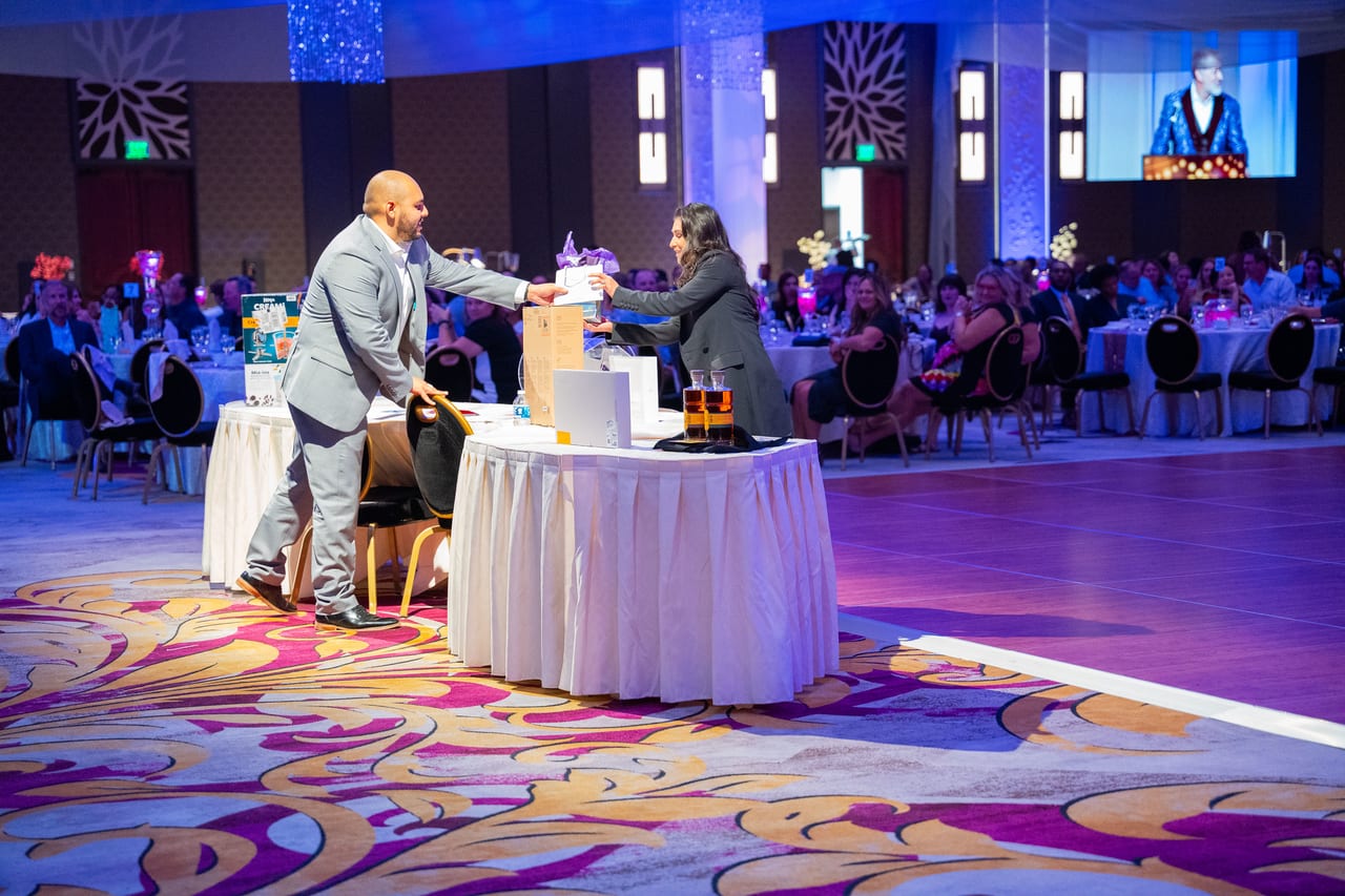 A prize handed across the table on the dance floor with the ballroom watching
