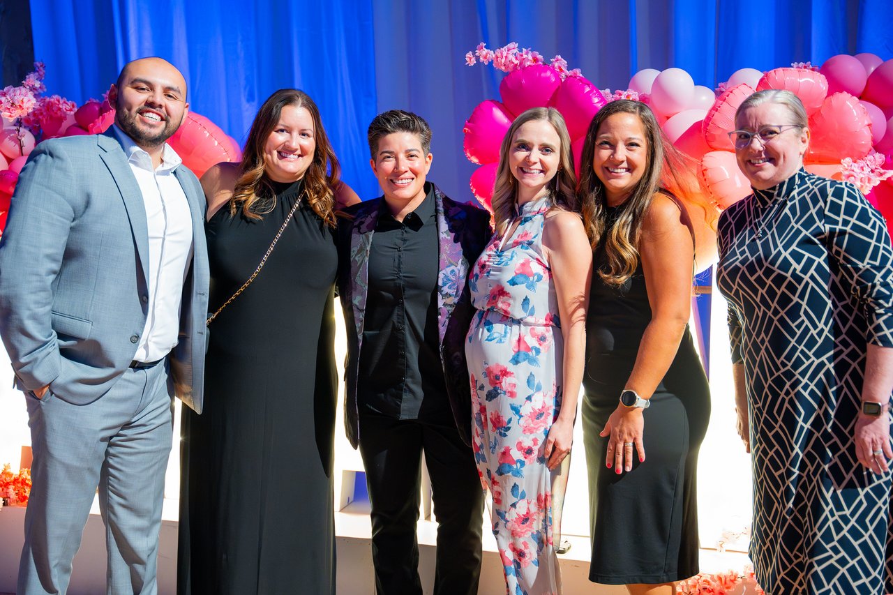 Six Renown coworkers posing together in front of the balloon wall