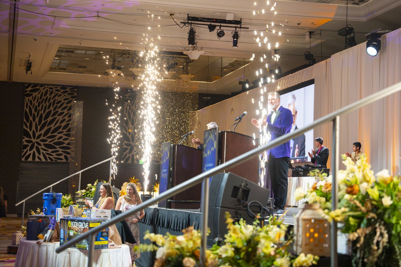 Cold spark fountains firing beside the stage as the host welcomes the room