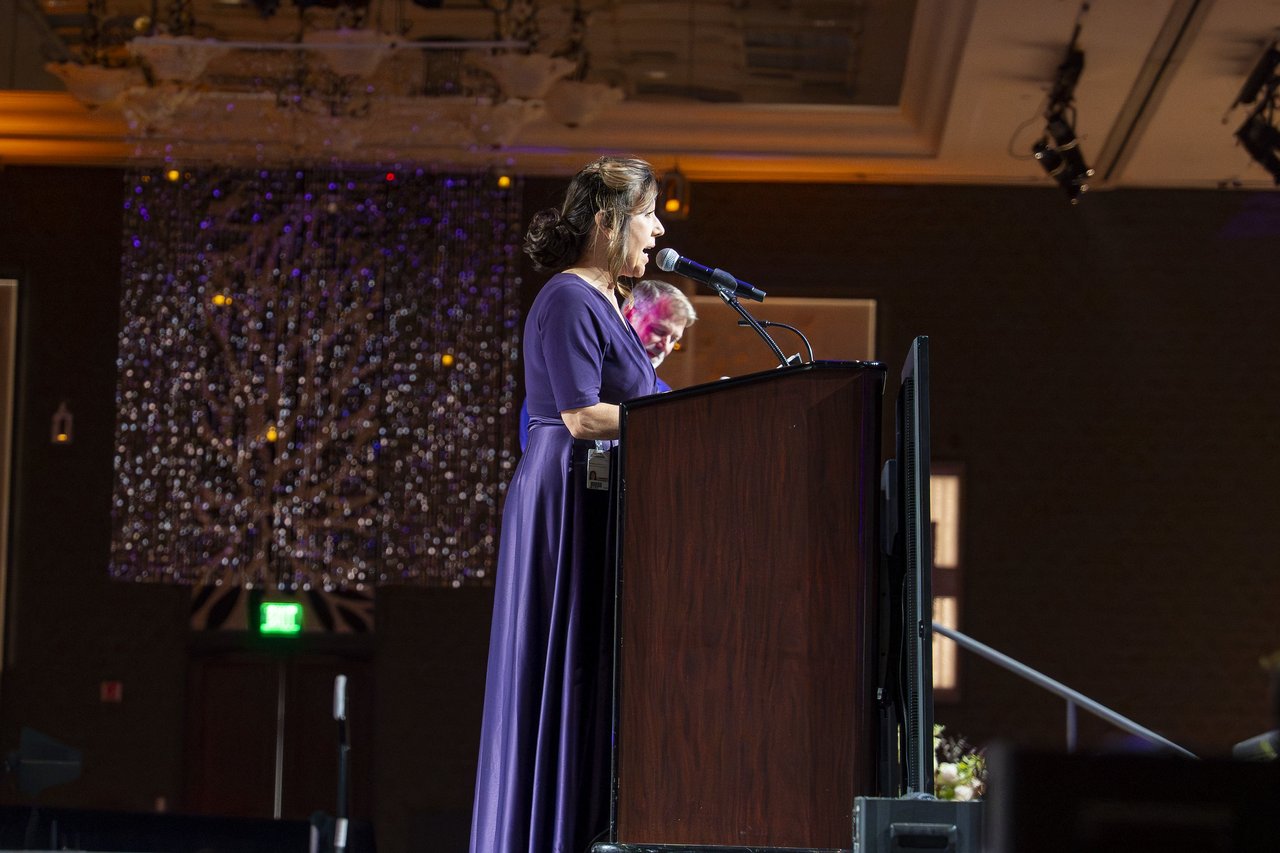 A Renown leader in a purple gown speaking at the podium