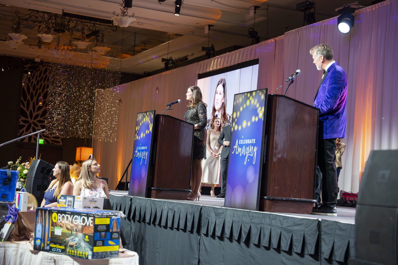 A Renown leader at the podium with the host beside her