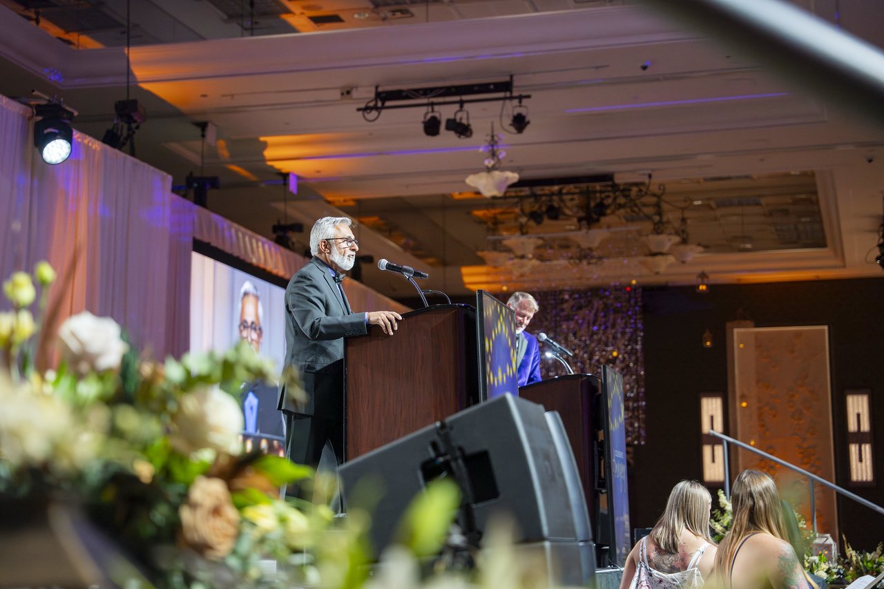 A Renown leader speaking at the podium seen past the stage flowers
