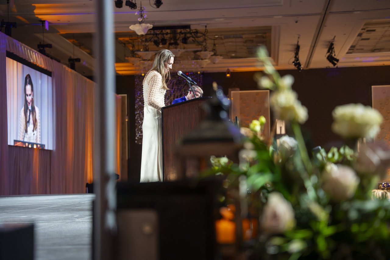 A Renown leader speaking at the podium past the flowers
