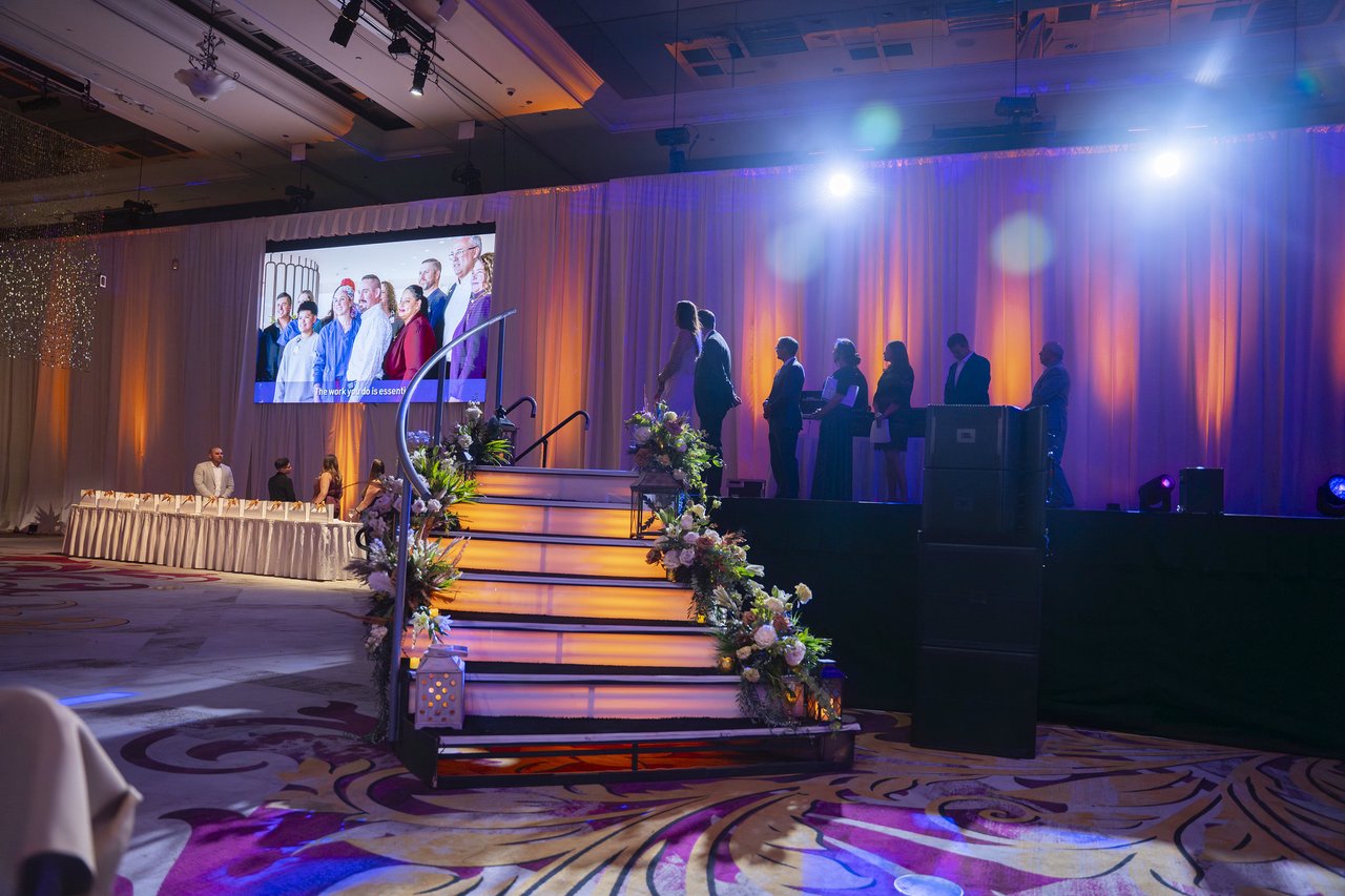 The lit stage stairs with honorees silhouetted under the big screen