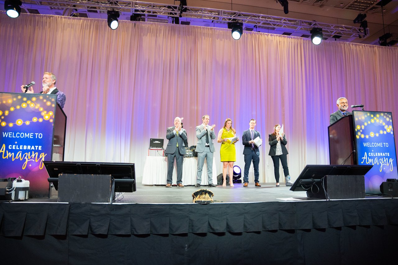 The full stage with both welcome podiums and the honorees between them